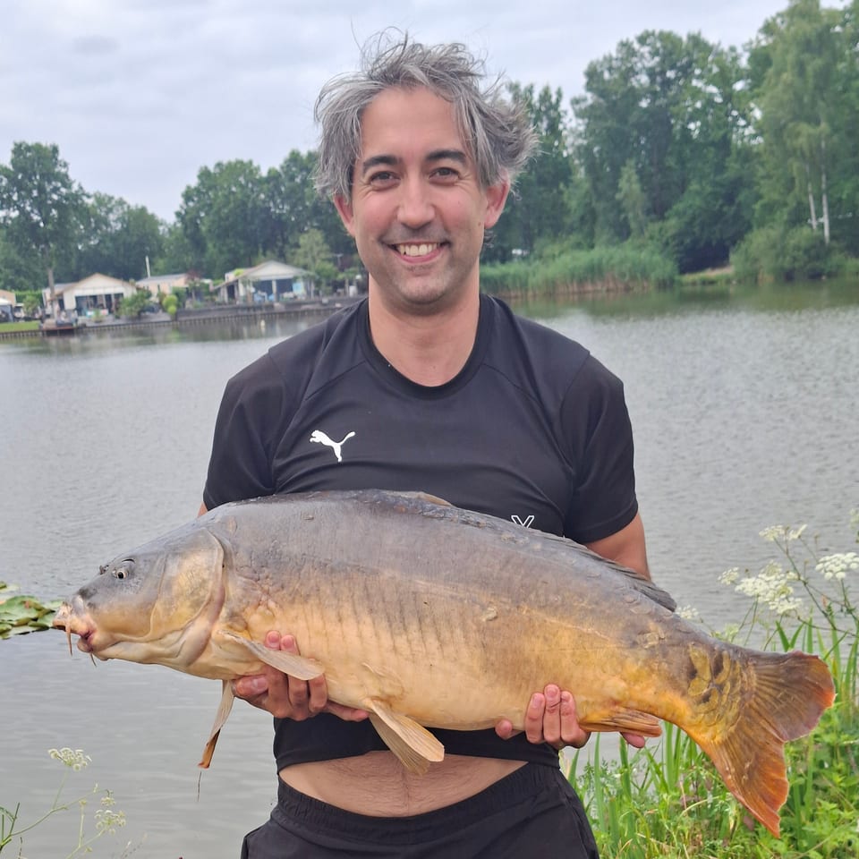 Jeroen Leidelmeijer holding a mirror carp on the bank of the Bijlmerweide