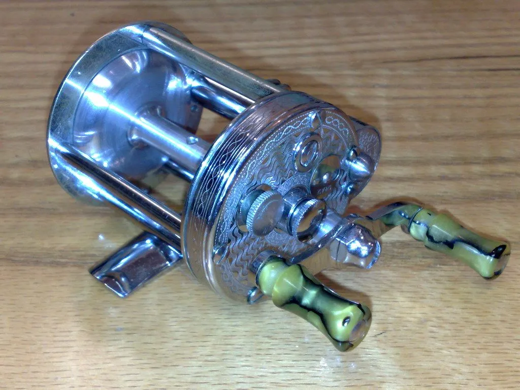 A round baitcasting reel seen from above: the spool sits across the frame, with a level-wind guide in front