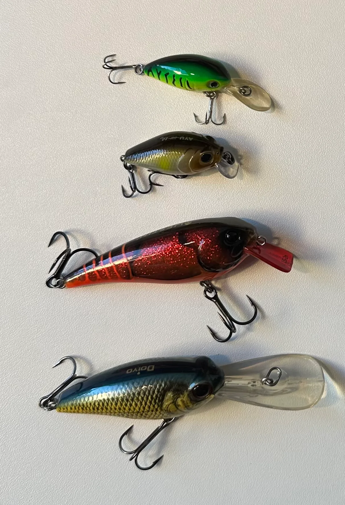Crankbaits of several sizes and colors laid out together, each hanging two treble hooks
