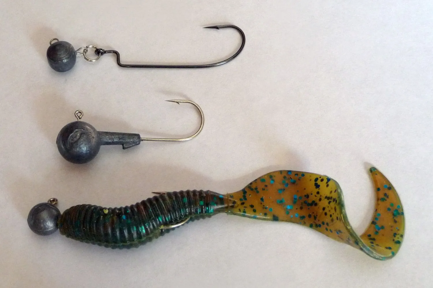 A lead jig head rigged with a soft-plastic curly-tail grub