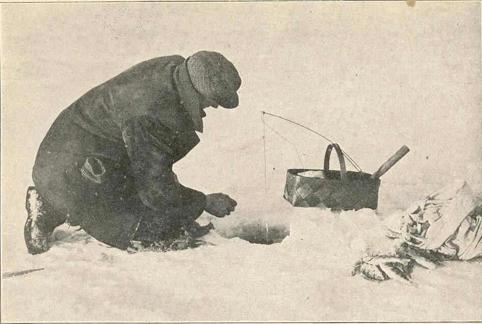 A fisherman kneeling at a hole in the ice of Lake Mendota in 1921, a basket beside him and a pile of perch on the snow