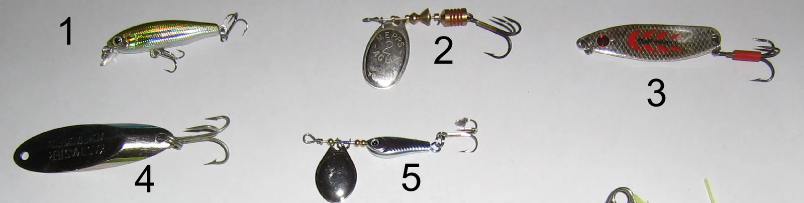 Five small lures numbered 1 to 5 on a white table: a holographic minnow plug, a Mepps Aglia No. 2 spinner, a painted spoon, a Kastmaster spoon and a small tail-spinner