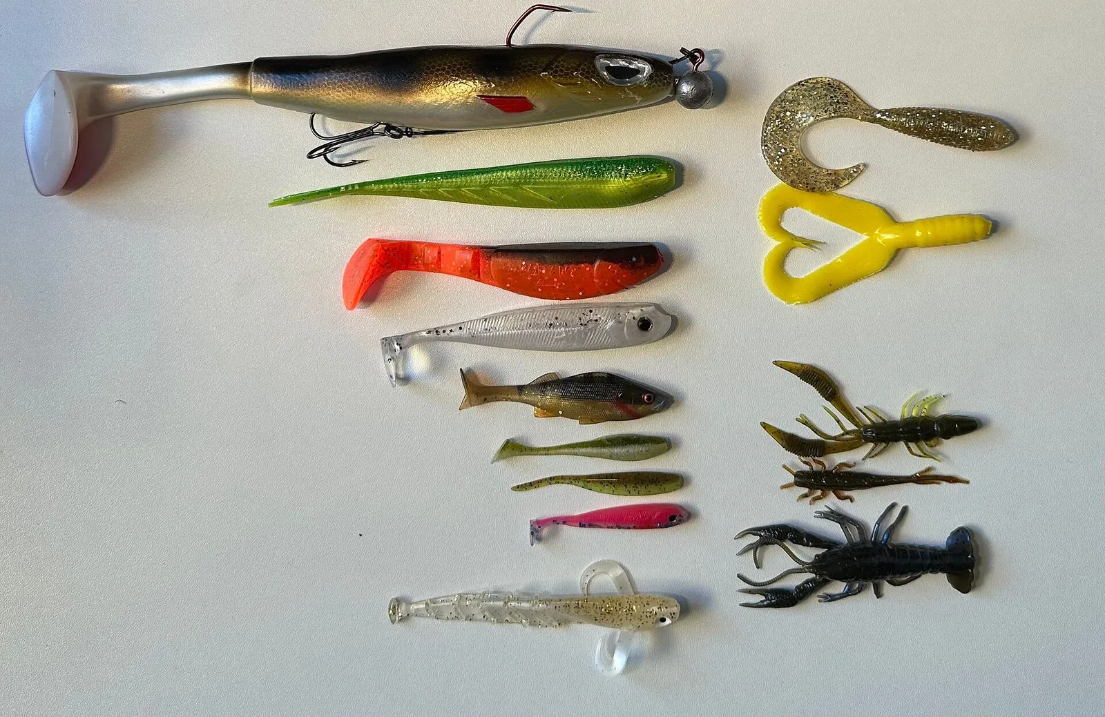 An assortment of soft-plastic lures: paddle-tail shads, curly-tail grubs, a craw and a creature bait