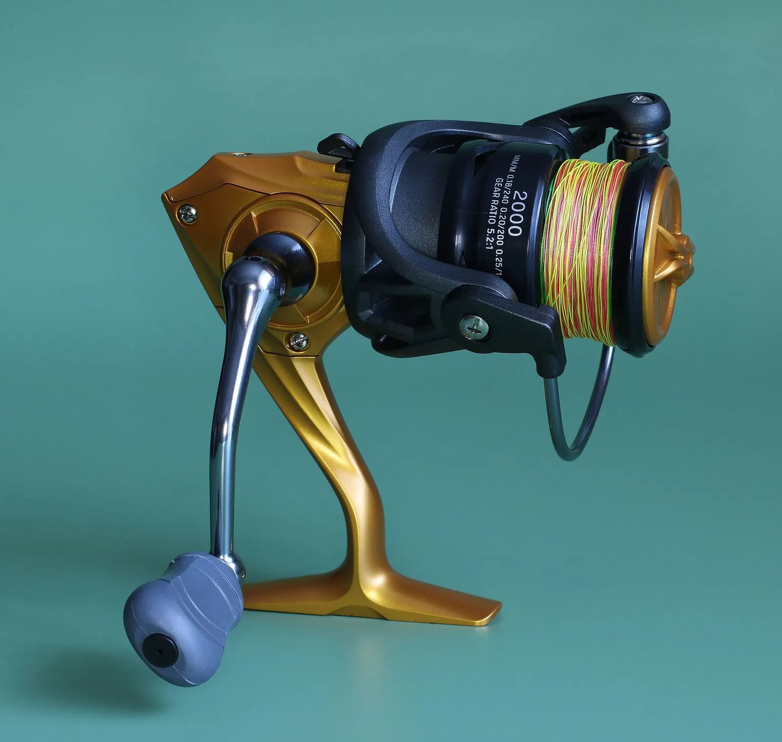 A spinning reel on a plain background: fixed spool at the front, bail arm, handle below